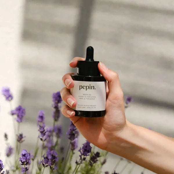 Neem olie, der holdes af en hånd med lavendel i baggrunden