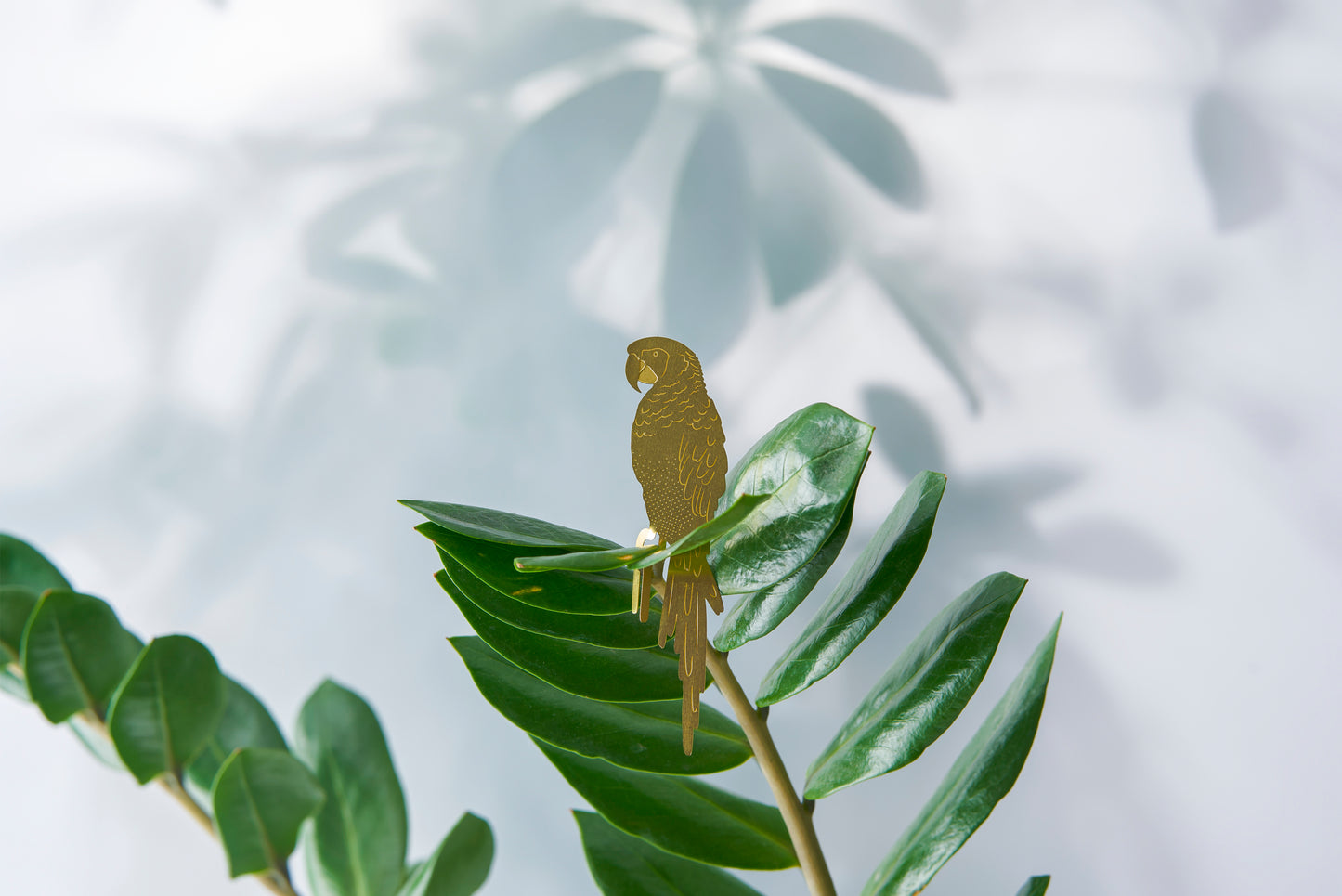 Papegøje i messing, der sidder i en plante og pynter